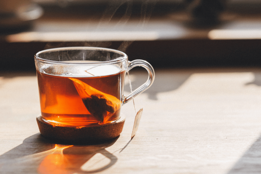 Eine dampfende Tasse Tee steht auf einem Holztisch