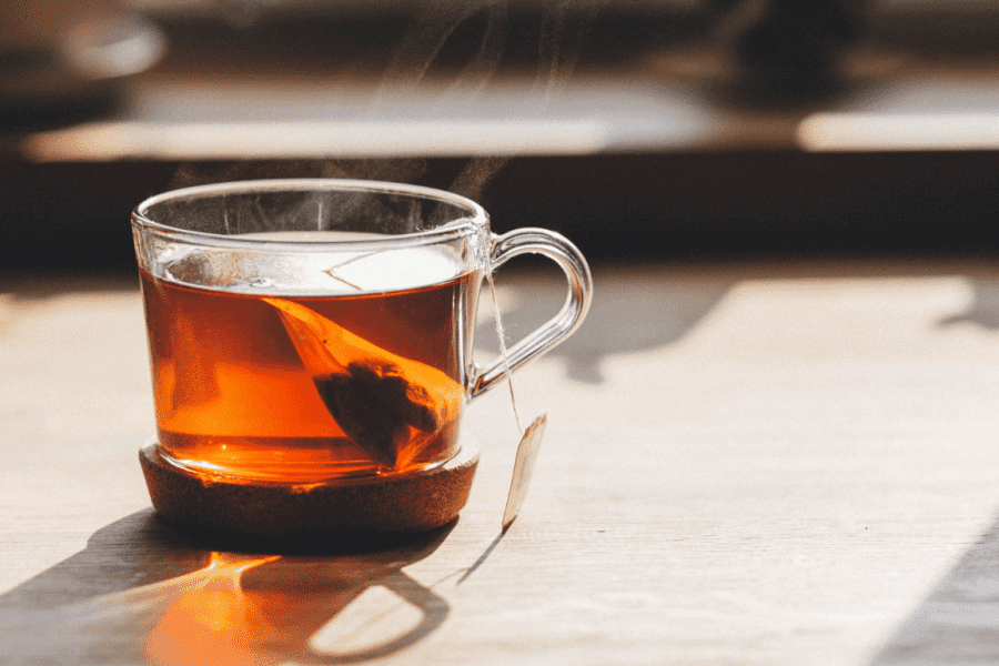 Eine dampfende Tasse Tee steht auf einem Holztisch