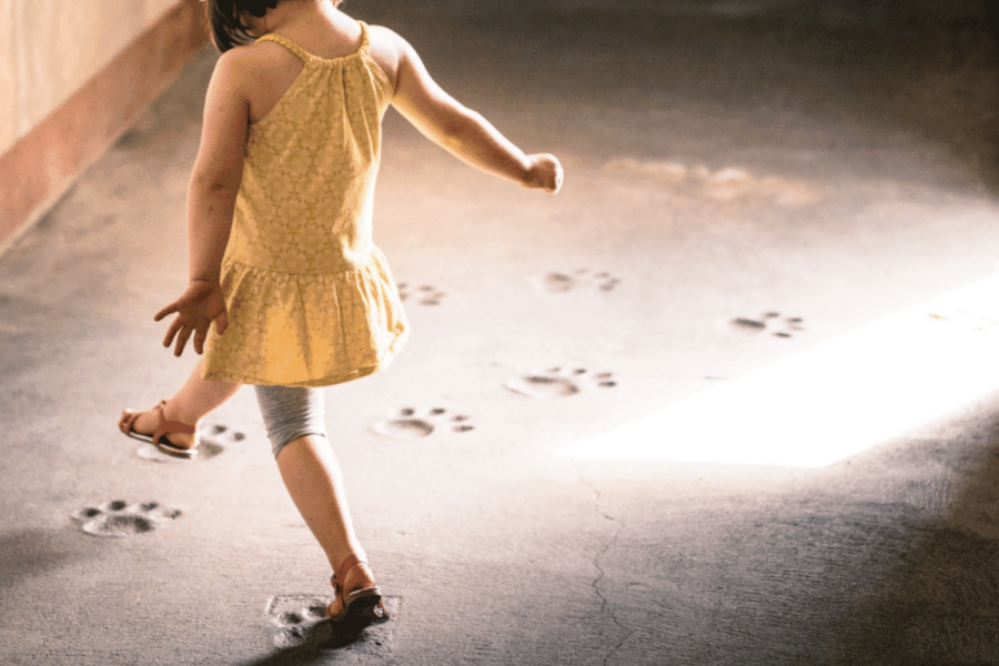 Ein Kind stapft tänzerisch Fußabdrücken hinterher.