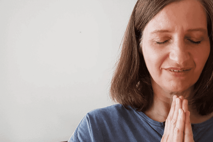 Melanie Jung mit geschlossenen Augen und Händen im Anjali Mudra vor der Brust.