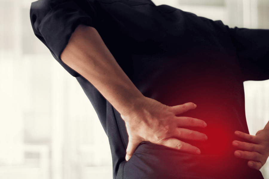 Volksleiden Rückenschmerzen: eine Person ist von hinten fotografiert und hält sich den schmerzenden Rücken