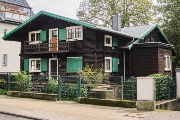 das Dore Jacobs Haus, ein dunkelbraunes Holzhaus mit grünen Fensterläden