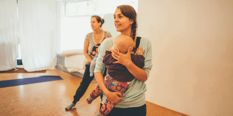 Zwei Mamas tanzen im Rückbildungskurs mit Baby im Arm