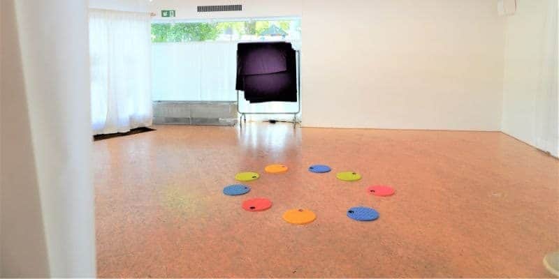 Im Tanzraum liegt ein Kreis aus bunten, runden Plättchen für den Unterrichtsbeginn im Kindertanz